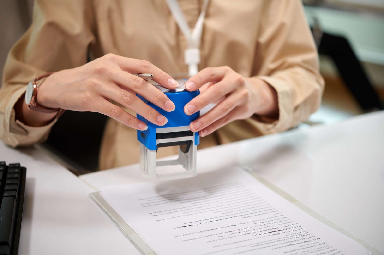 Person pressing a stamp onto an official document at an office desk.